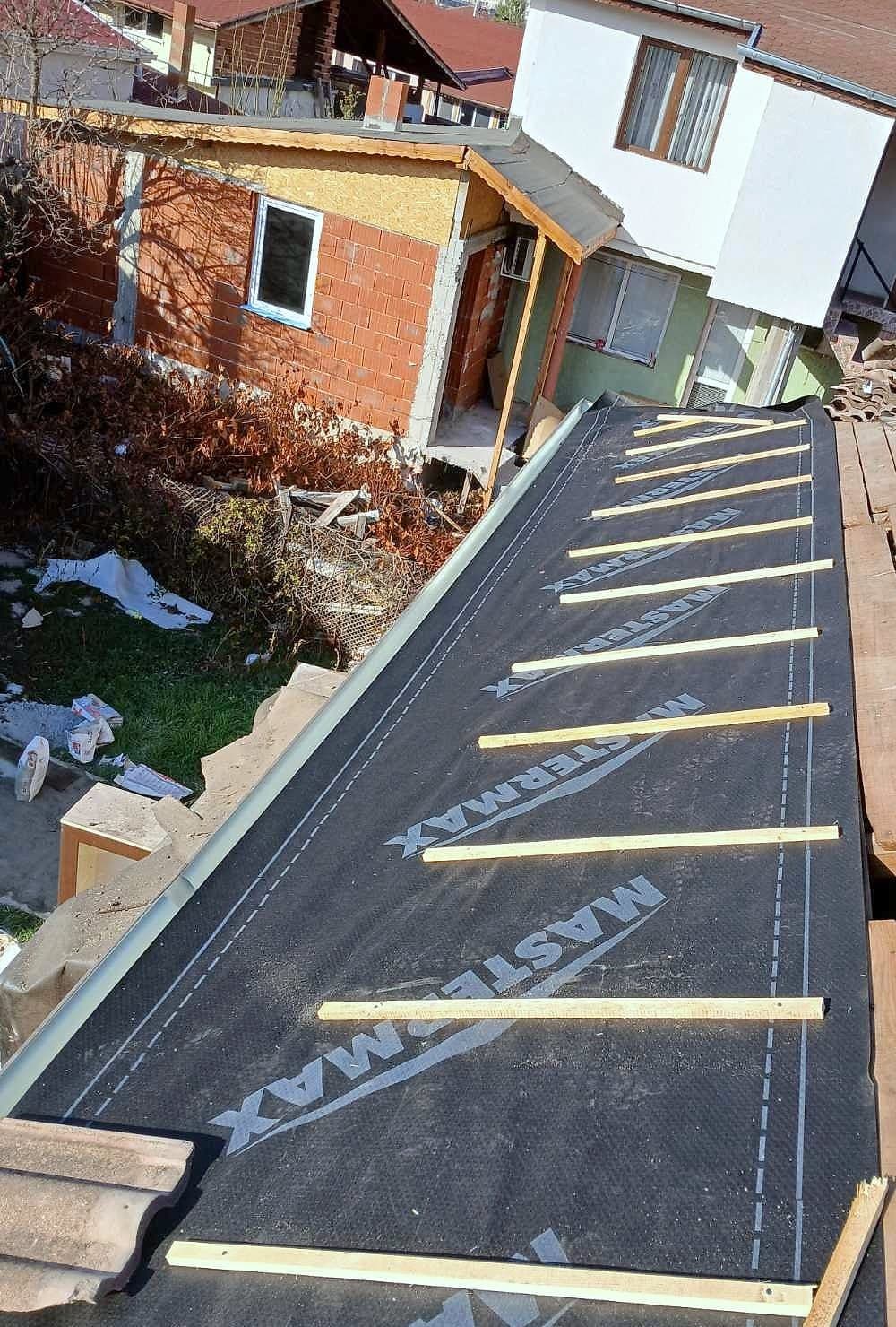 Black waterproof roofing membrane over the roof boarding, with counter-battens nailed in place running up the slope