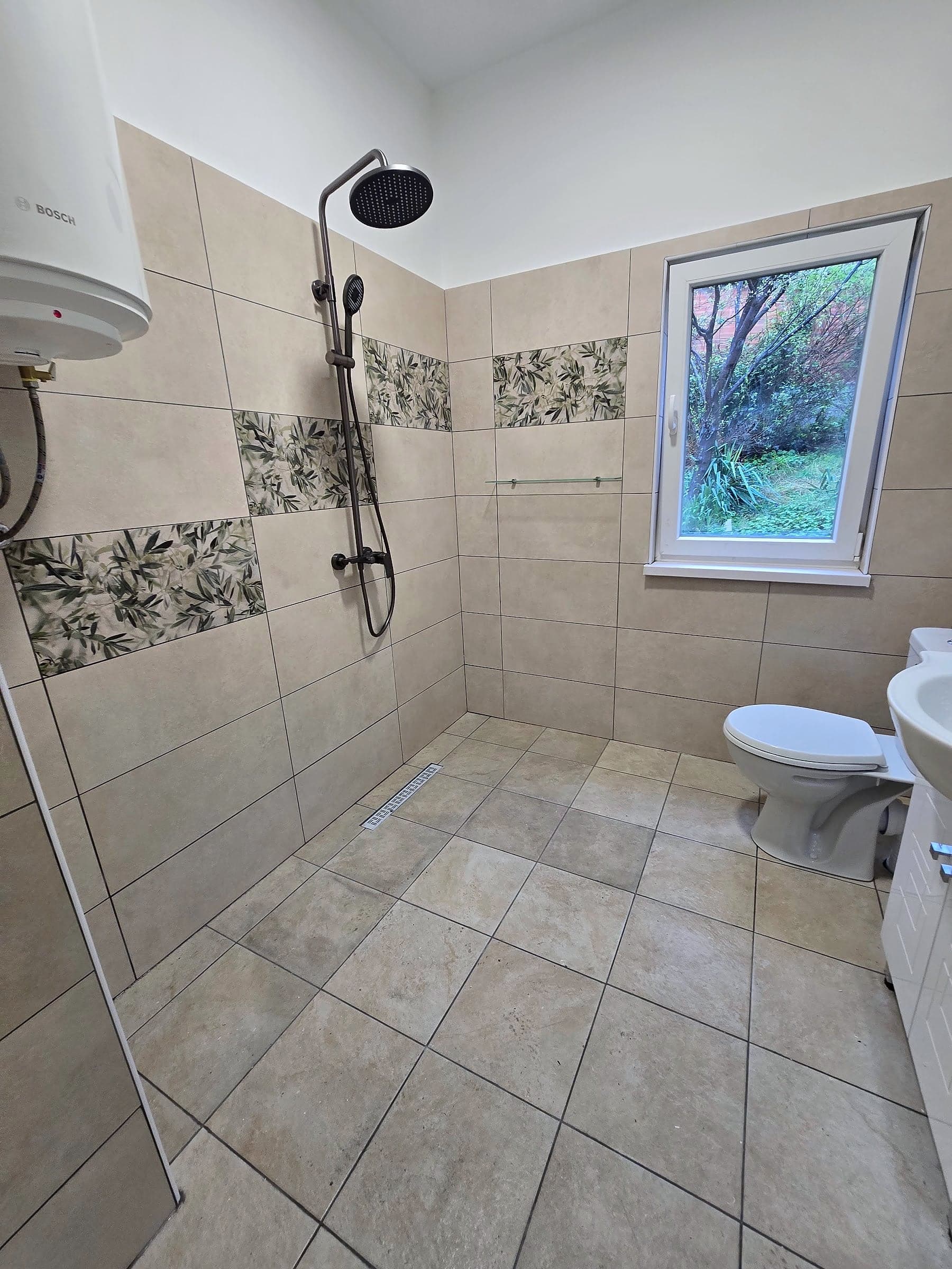 Bathroom in Knyazhevo with decorative tiles — Black shower system and water heater