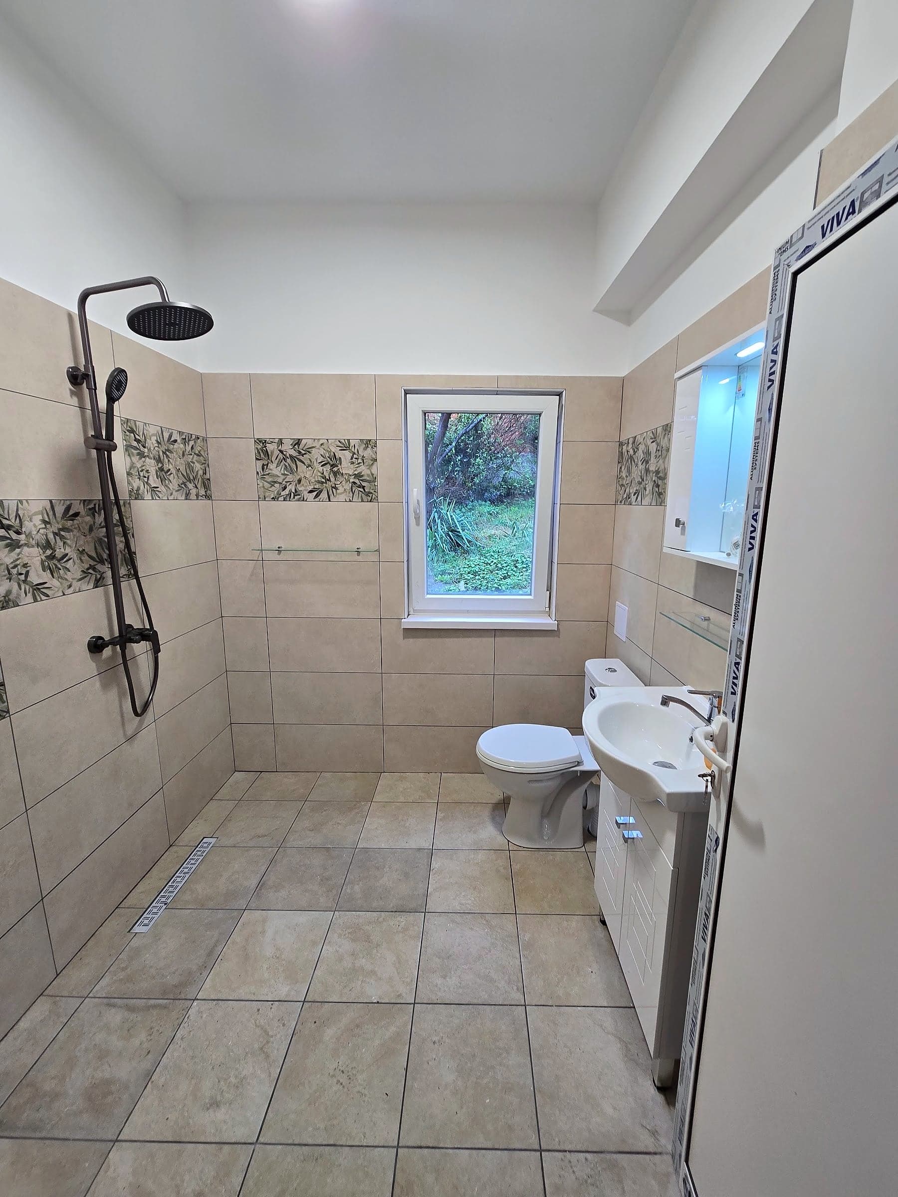 Bathroom in Knyazhevo with decorative tiles — Washbasin, toilet and window
