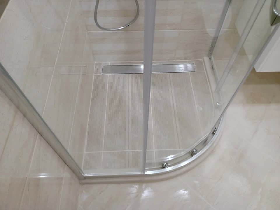 Bathroom with a shower enclosure and a wall-hung toilet — Shower enclosure with a linear drain