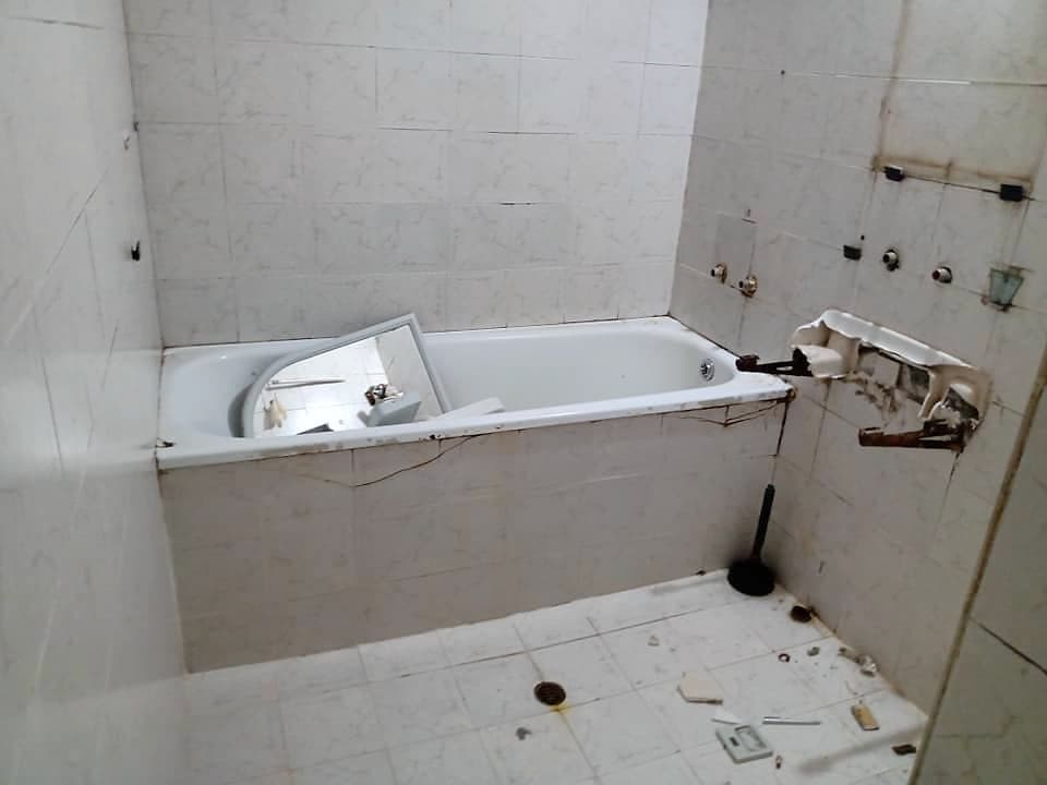 Bathroom with a shower enclosure and a wall-hung toilet — Before the renovation: the old bathtub