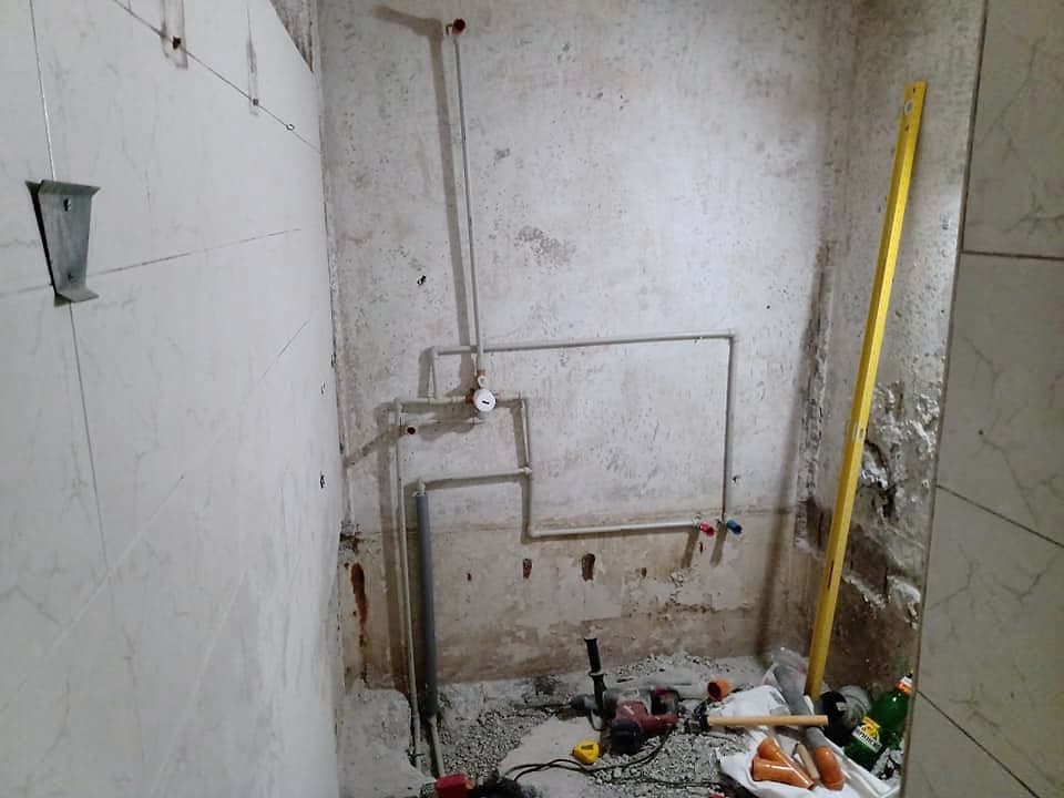 Bathroom with a shower enclosure and a wall-hung toilet — The new water pipes during the renovation
