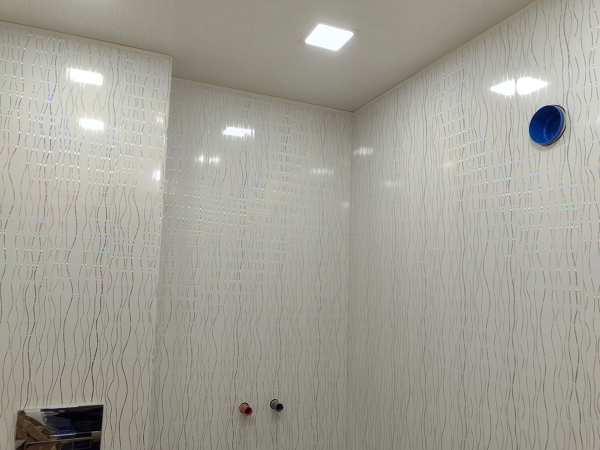Bathroom with a wall-hung toilet and textured tiles — LED panels in the ceiling