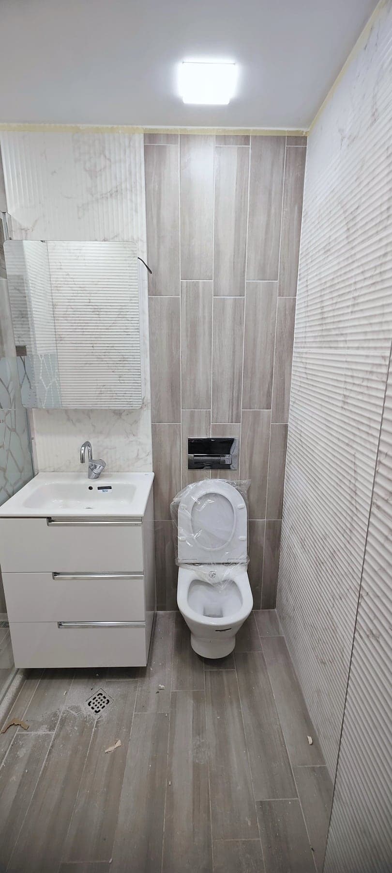 Bathroom with wood-effect and white textured tiles — Vanity unit and toilet