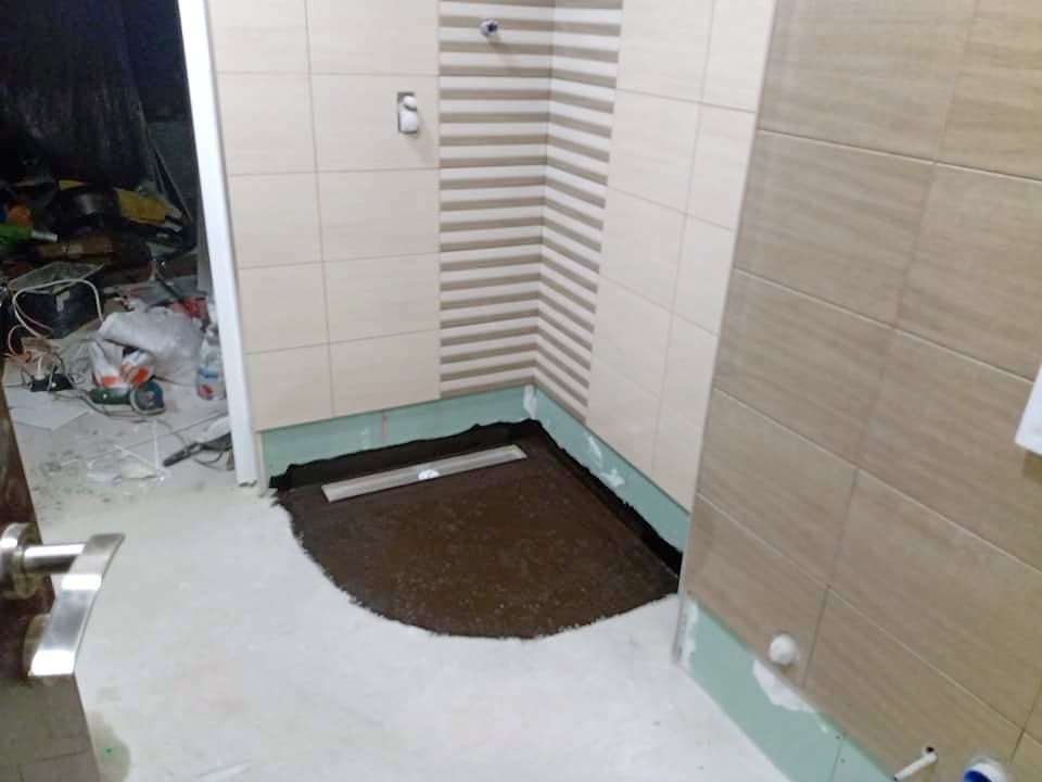 Beige and brown bathroom with a shower enclosure — Shower area with a linear drain during the renovation