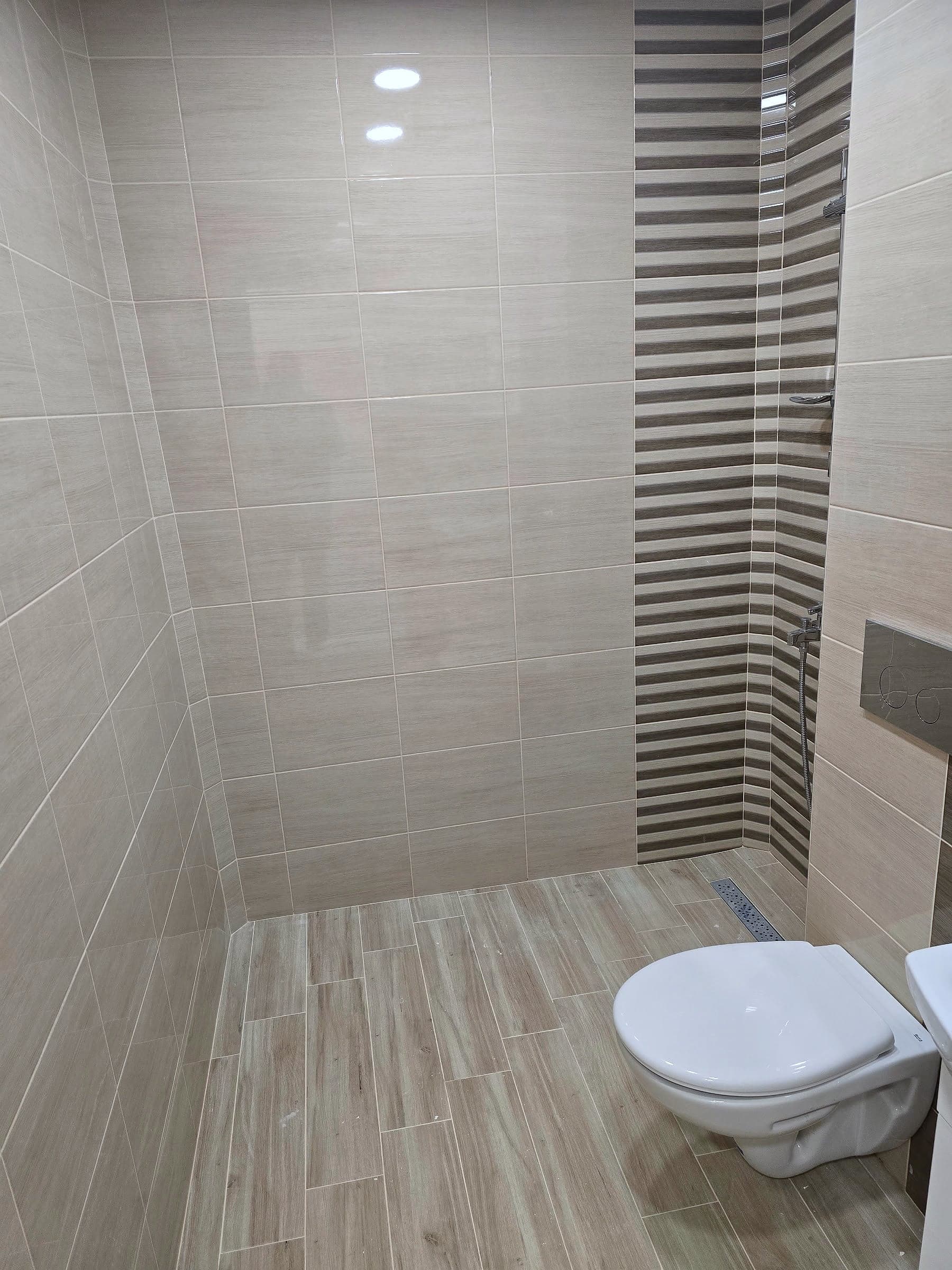 Bathroom in Sveta Troitsa: beige with a wood-effect floor — Wall-hung toilet and linear drain