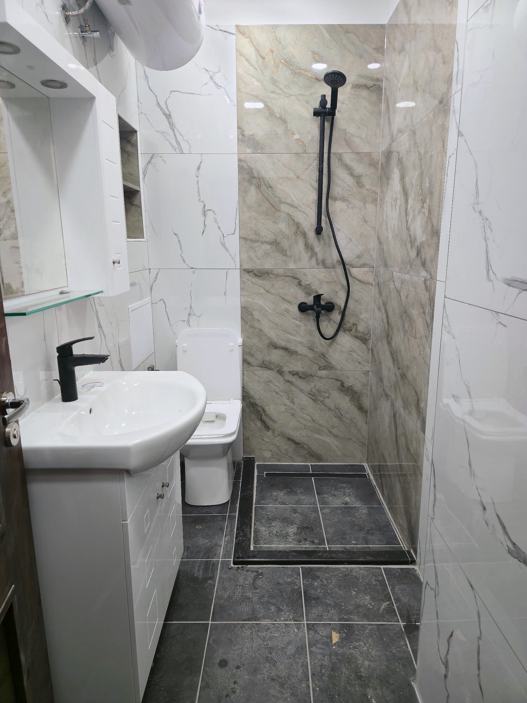 White and grey marble bathroom with black taps — Walk-in shower area and black taps