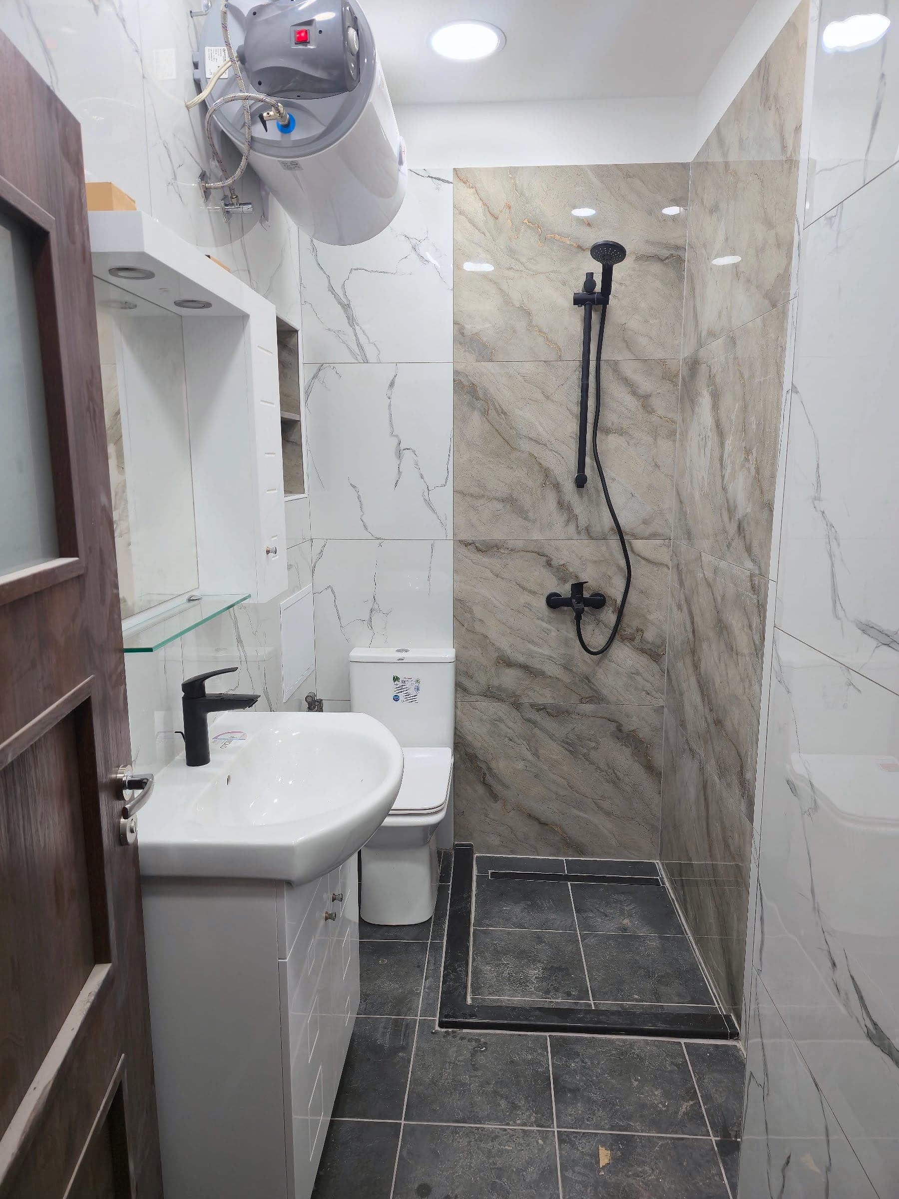 White and grey marble bathroom with black taps — General view