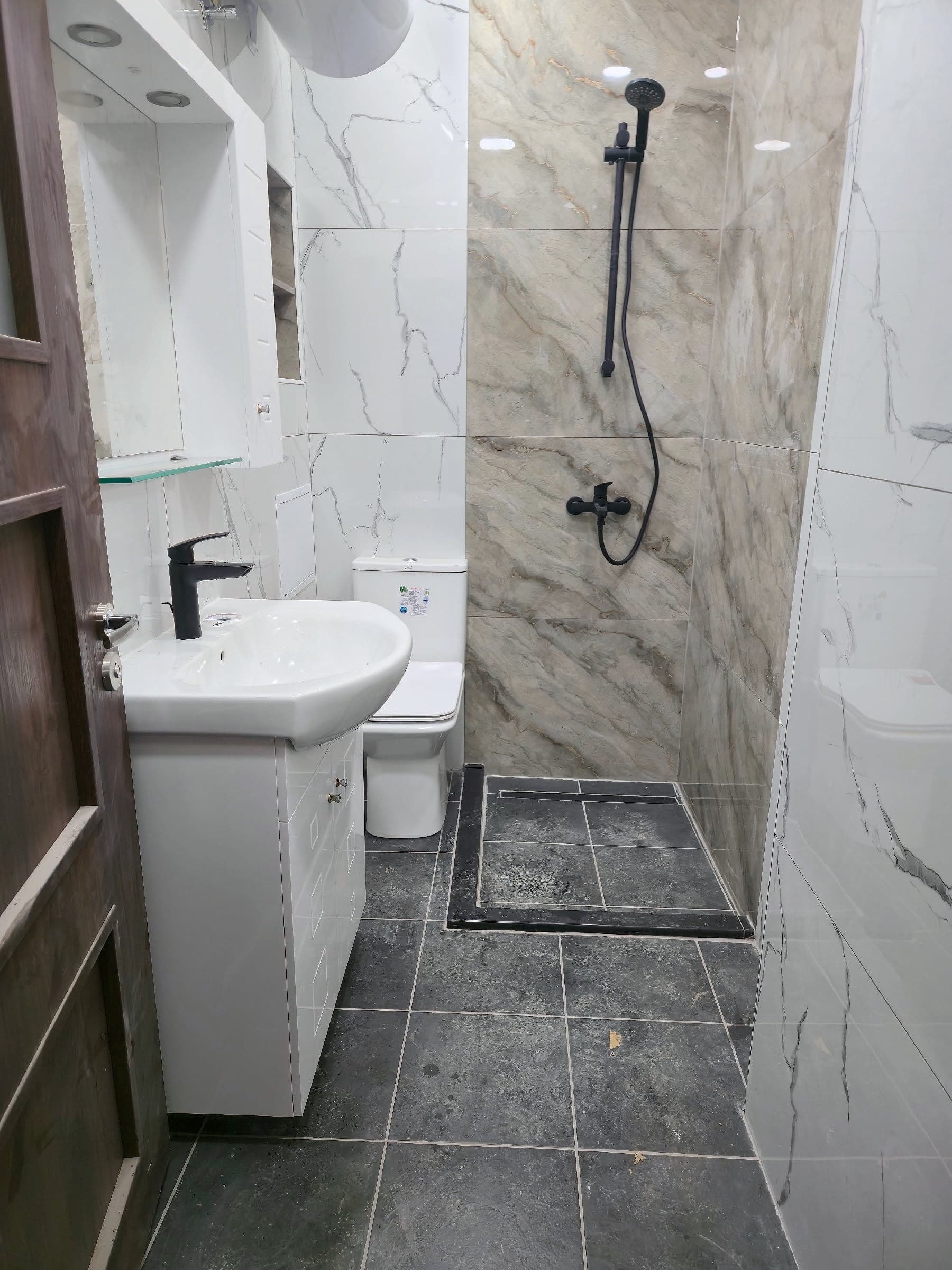 White and grey marble bathroom with black taps — Washbasin and shower area
