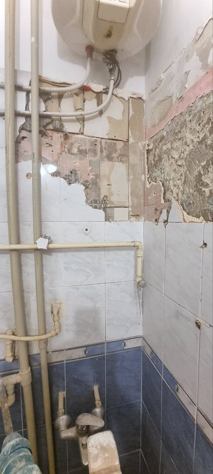 White and grey marble bathroom with black taps — Before the renovation: the old tiles and pipes