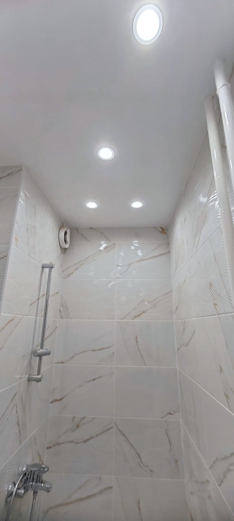 White marble bathroom with a round basin — Shower area