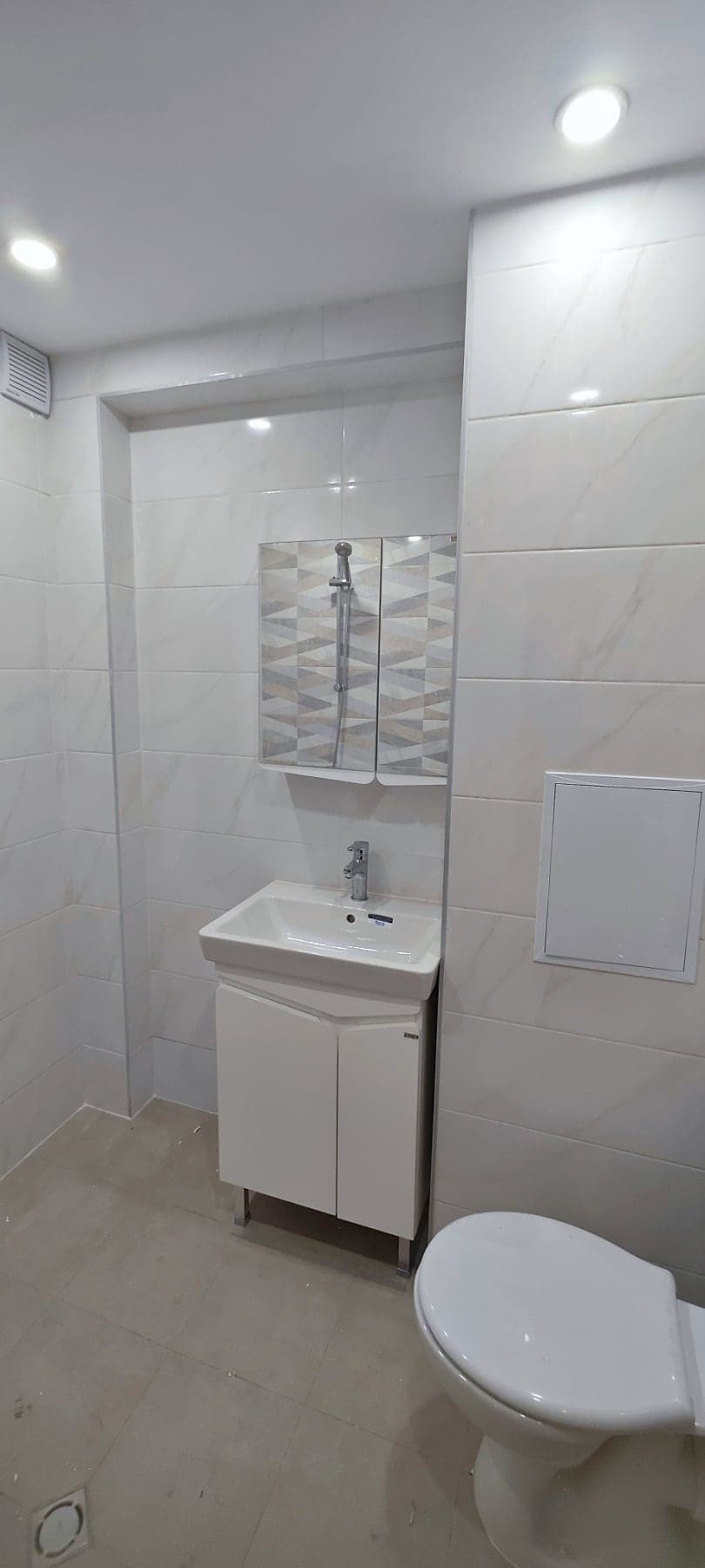White bathroom with triangle-pattern tiles — General view