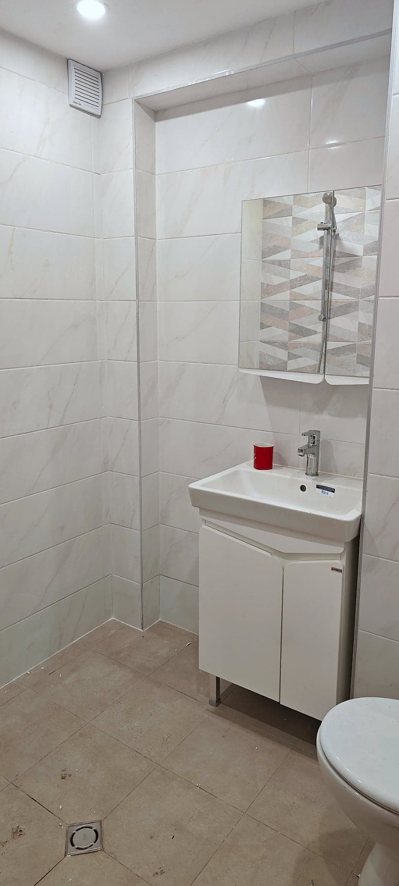 White bathroom with triangle-pattern tiles — Vanity unit and mirror cabinet