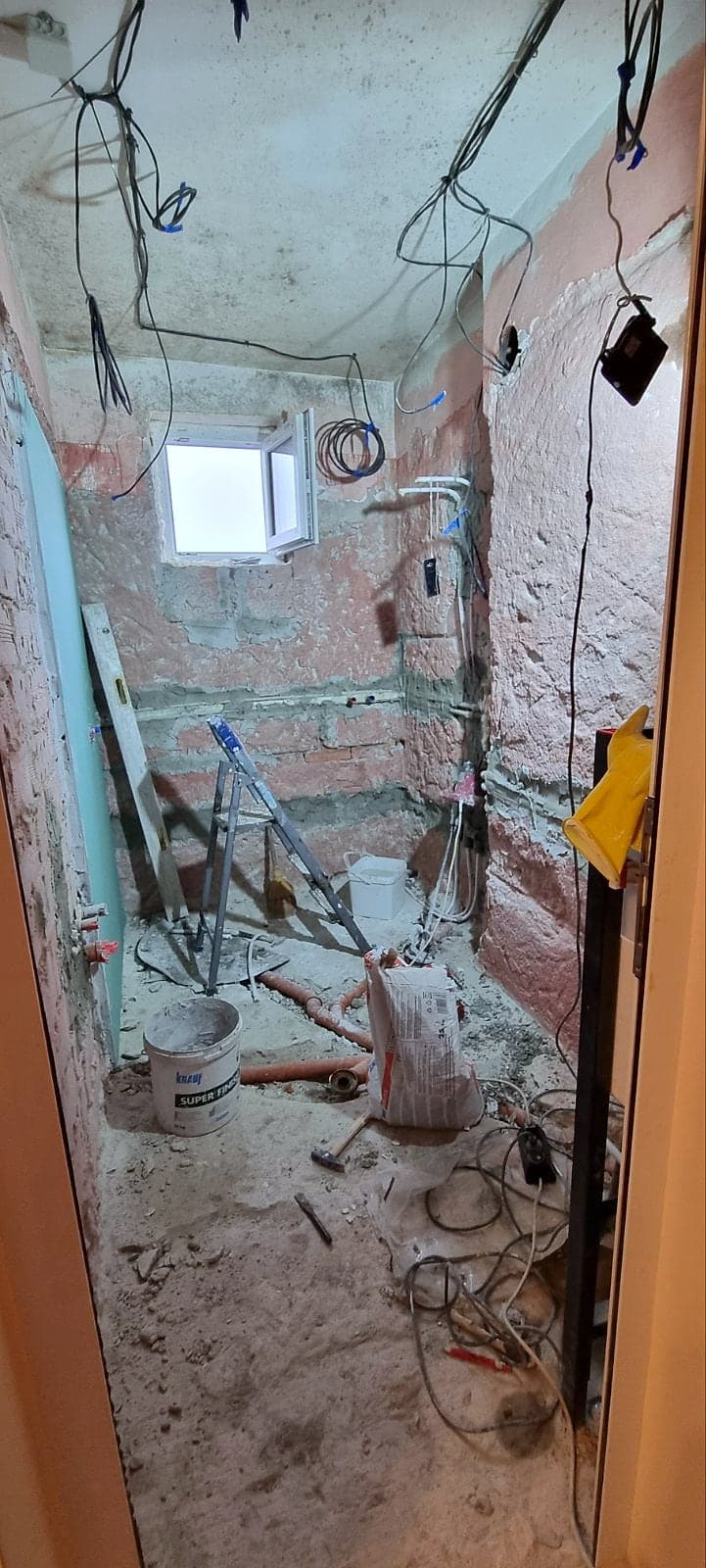 Тясна баня с тухлени стени, нови тръби и кабели по време на ремонта