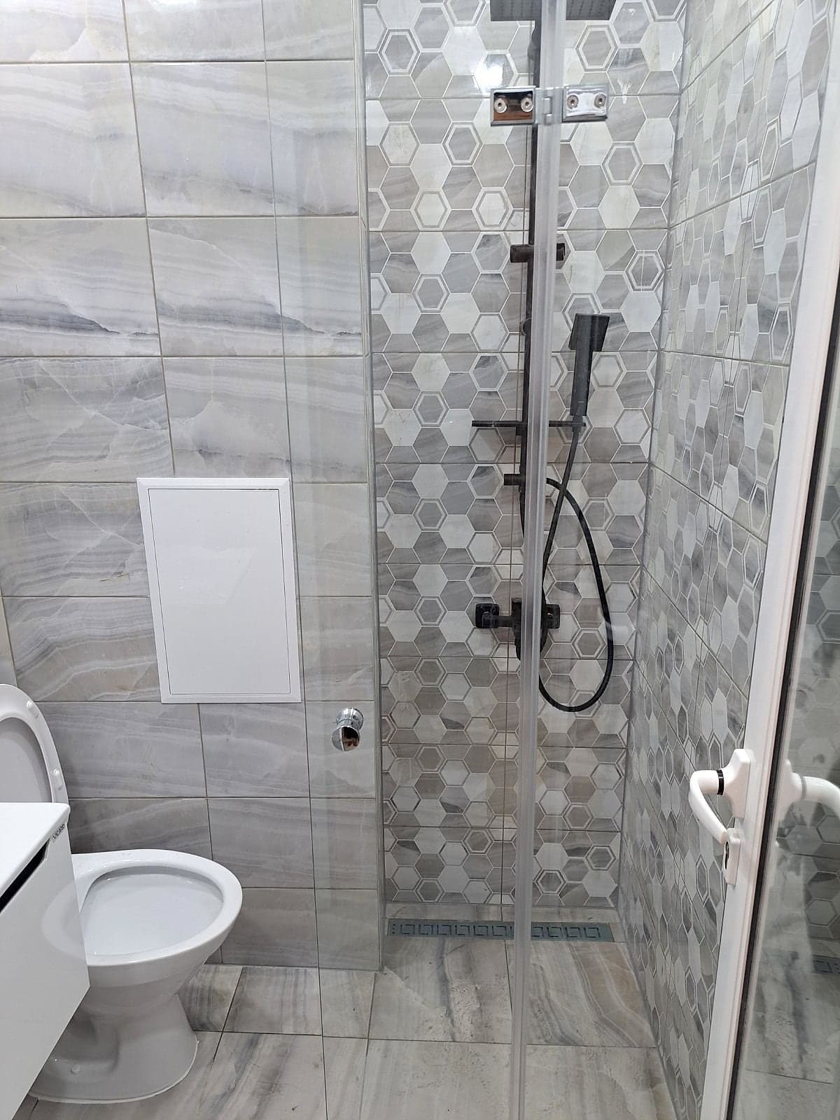 Grey bathroom with hexagon tiles and black taps — Shower enclosure with hexagon tiles