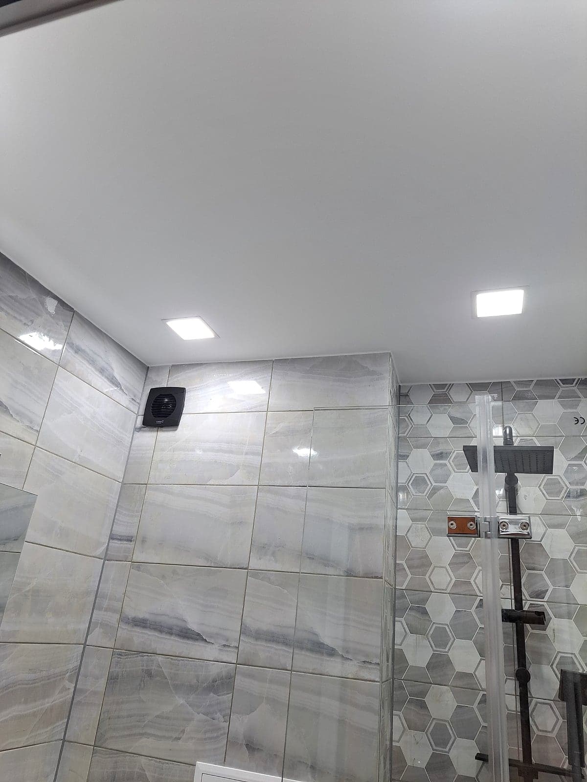 Grey bathroom with hexagon tiles and black taps — Ceiling with LED lighting
