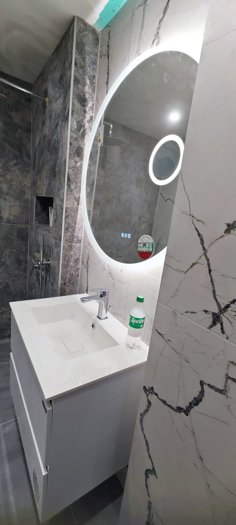 Dark stone and white marble bathroom with an LED mirror — Vanity unit and round LED mirror